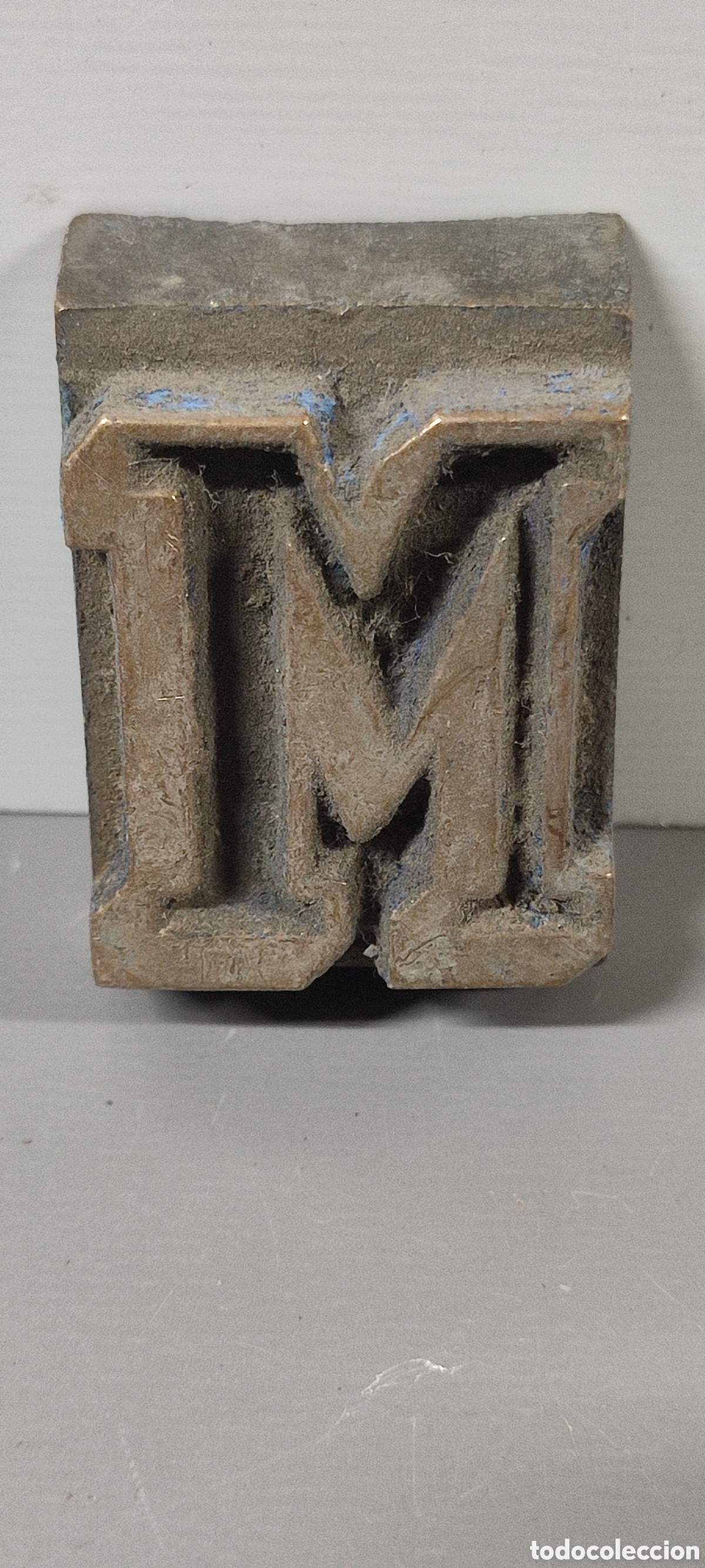 Antig&uuml;edades: Antigua letra tipogr&aacute;fica M de bronce. Mide aproximadamente 3 x 5 cm.