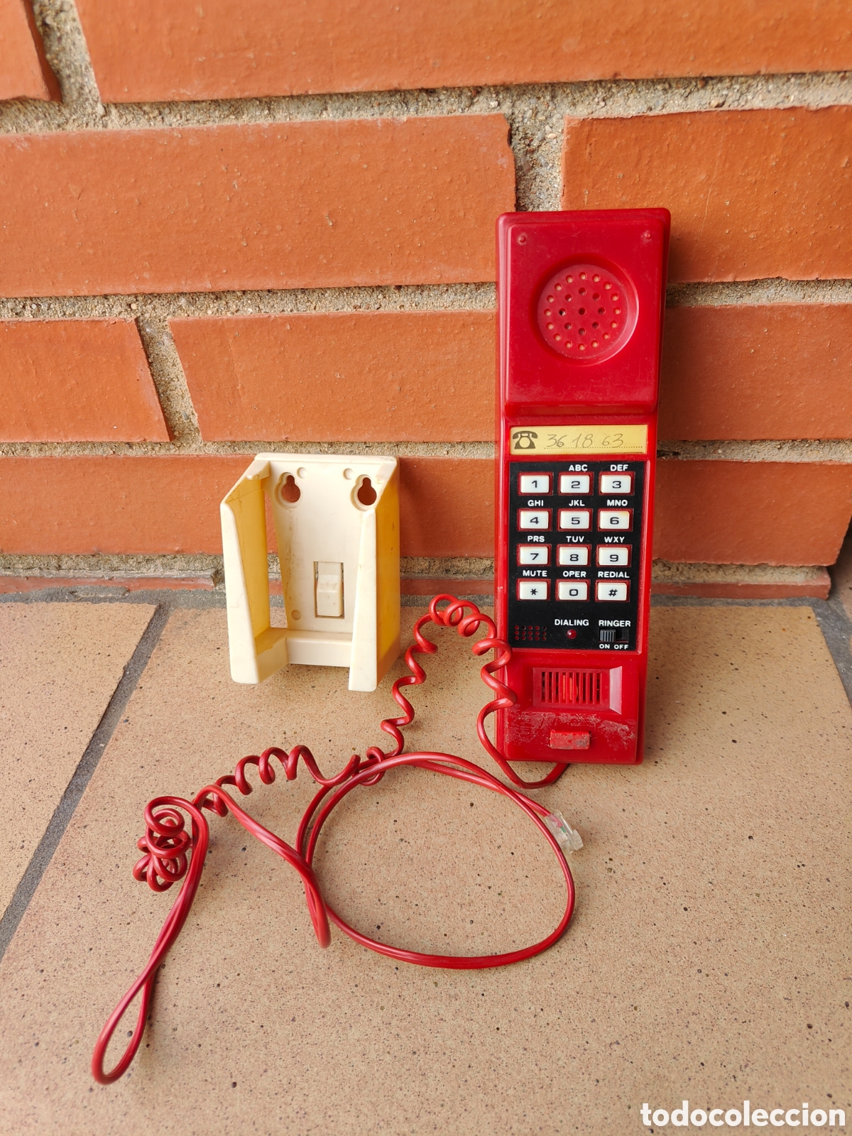 Tel&eacute;fonos: Antiguo tel&eacute;fono fijo de pared color rojo con las teclas cuadradas blancas soporte de pared incluido