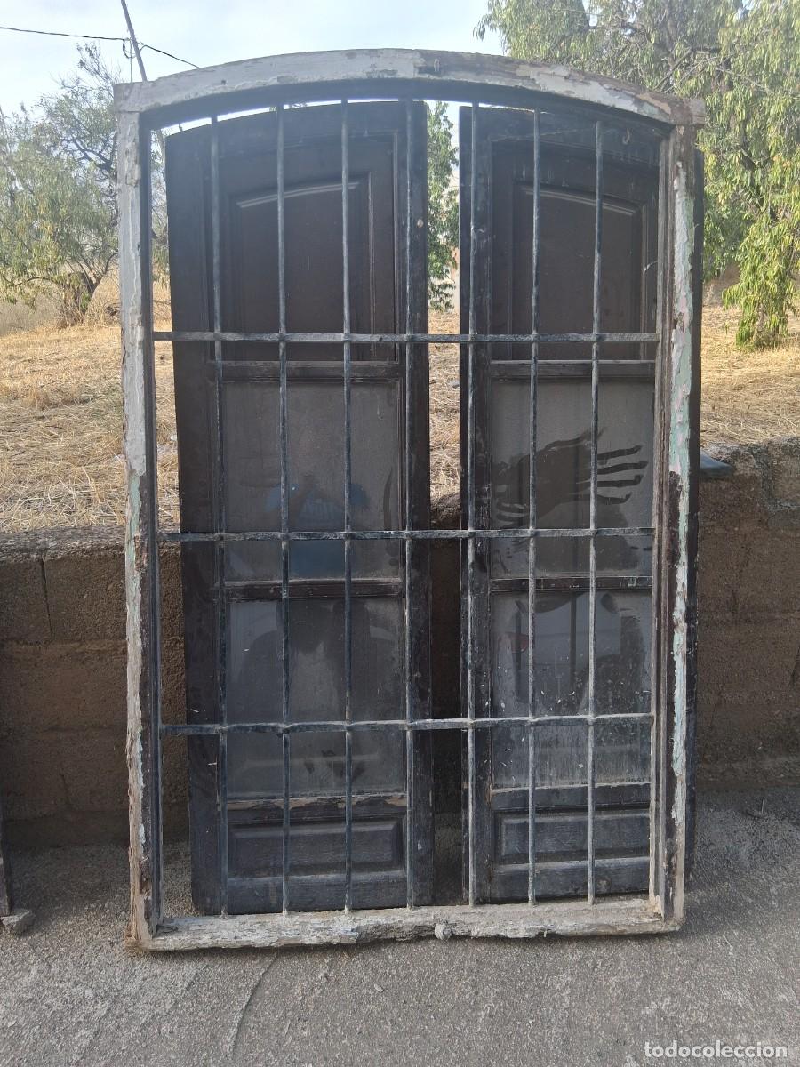 Antig&uuml;edades: Ventana antigua de madera con estructura de medio punto y una reja de hierro forjado integrada