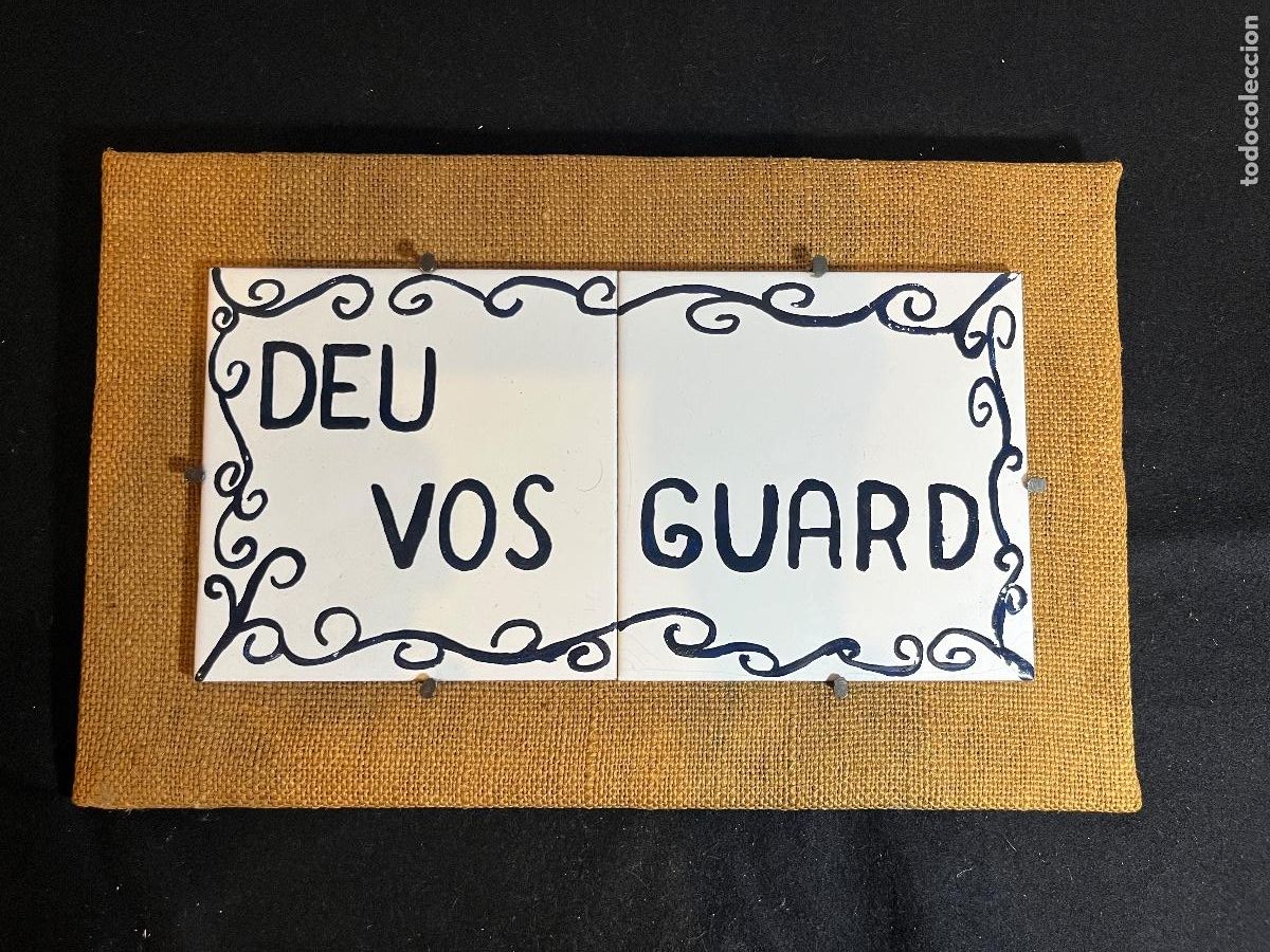 Antig&uuml;edades: Cartel decorativo catal&aacute;n &ldquo;DEU VOS GUARD&rdquo; con dos azulejos blancos esmaltados sobre tela de saco &ndash; a