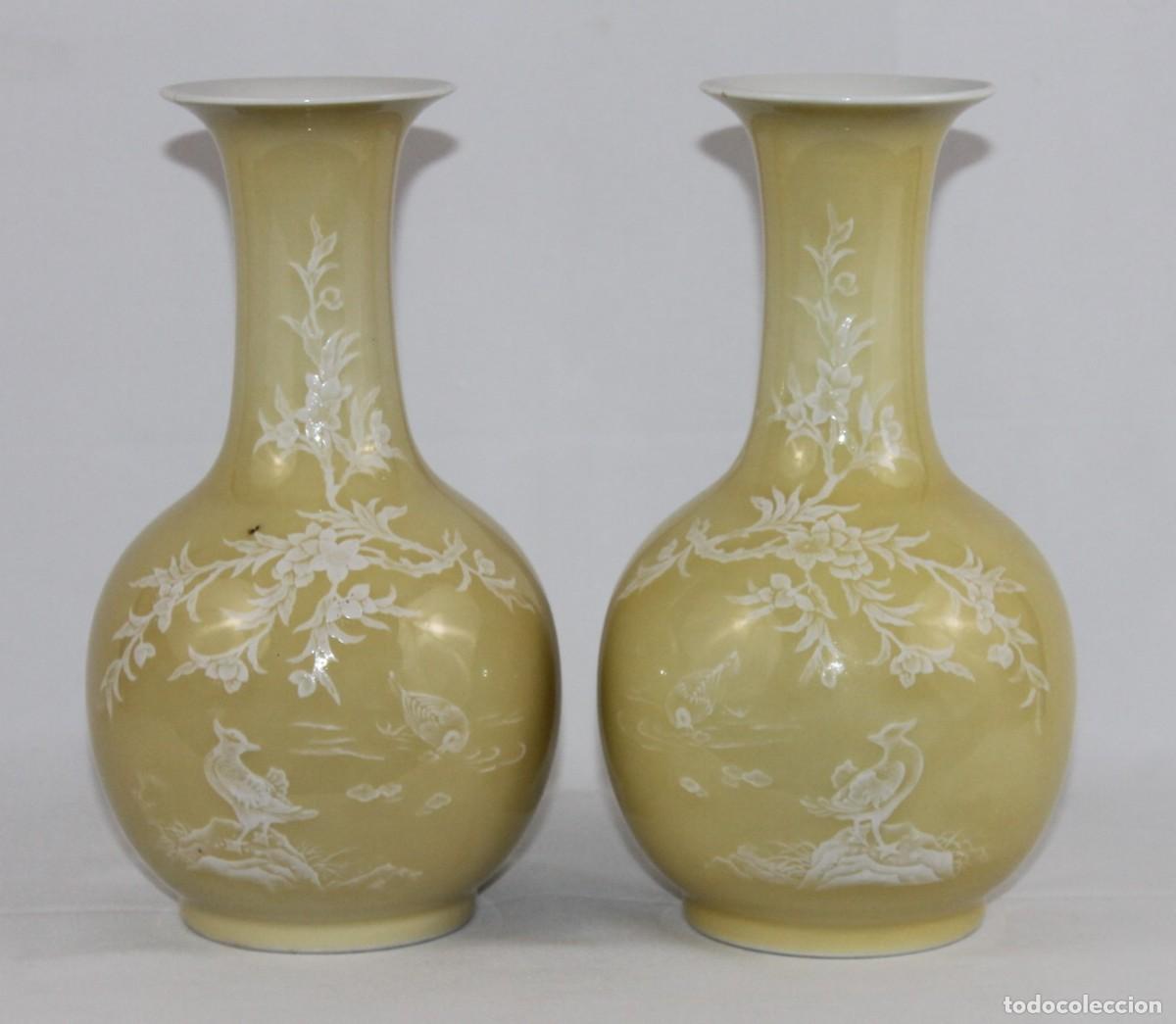 Antigüedades: Pareja de jarrones chinos. Porcelana con esmalte amarillo y decoración blanca. Sello en base.