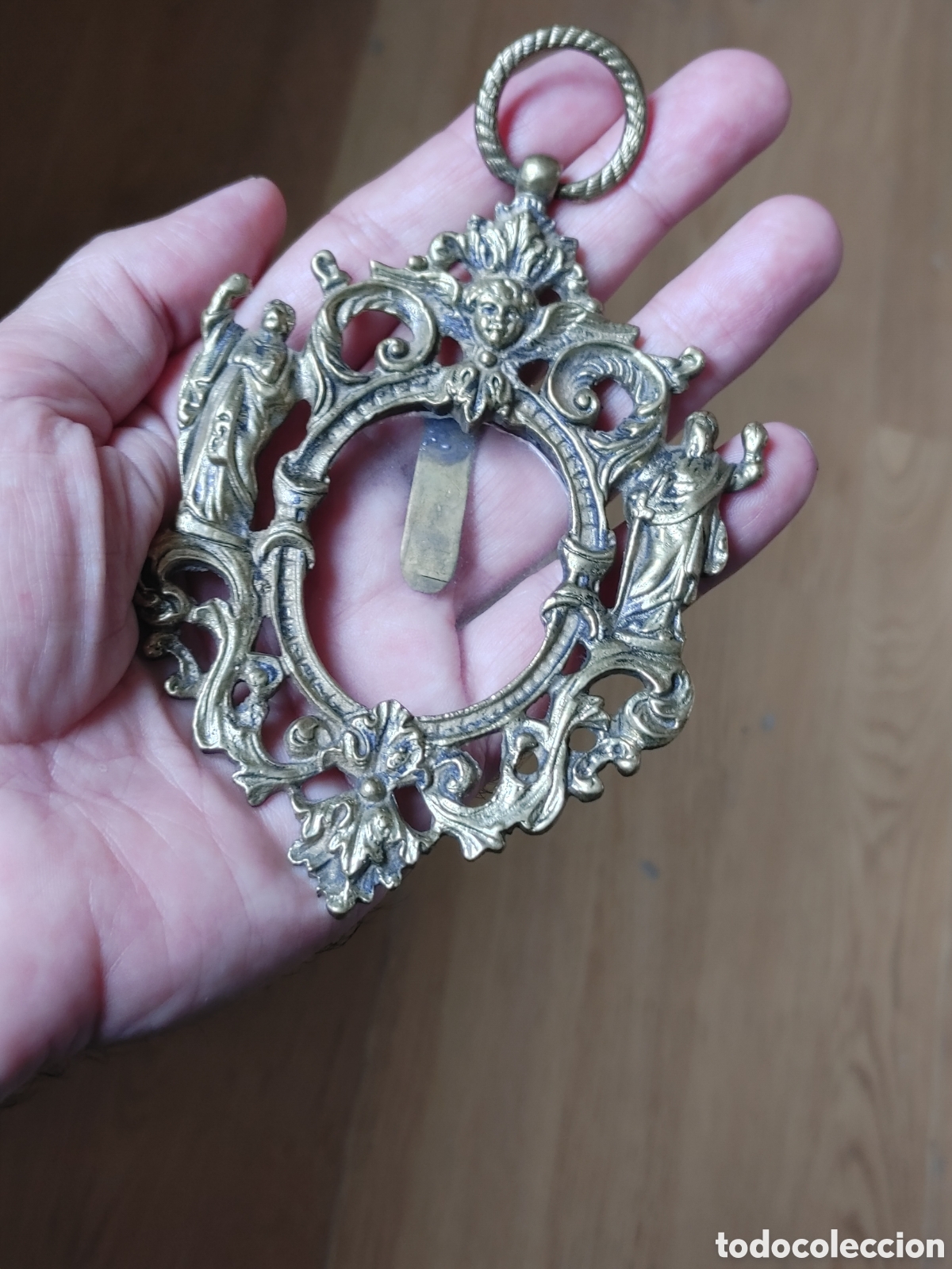 Antig&uuml;edades: Porta relicario en bronce dorado y calado. Con querubin y dos santos. S. XVIII.