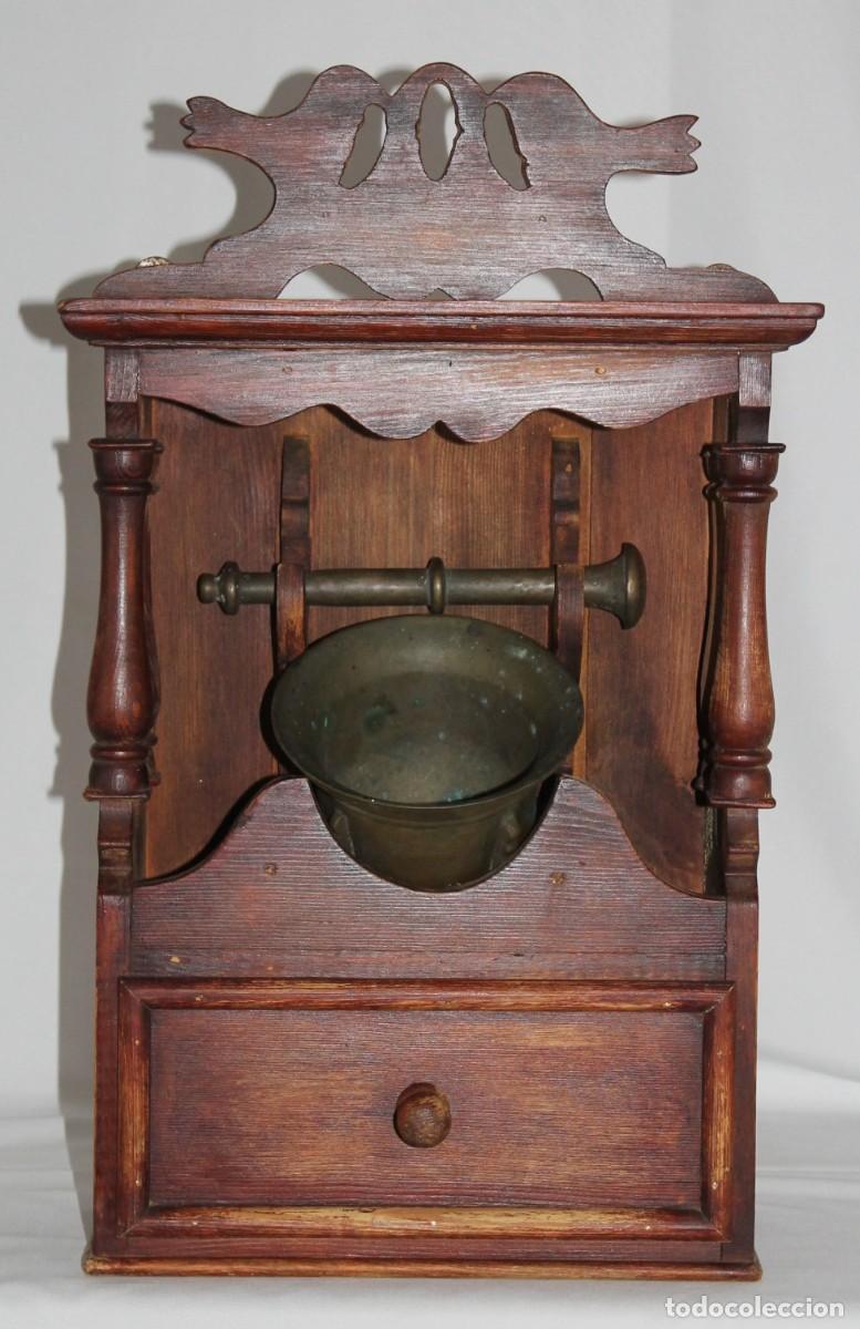 Antig&uuml;edades: Mortero de bronce con mano y mueble soporte de madera con caj&oacute;n. Principios siglo XX