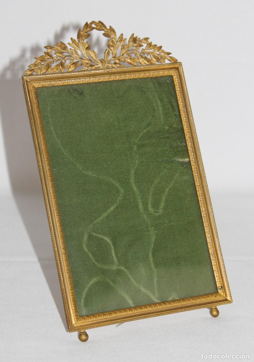 Antig&uuml;edades: Marco de sobremesa en bronce estilo Imperio con copete decorativo. Siglo XX