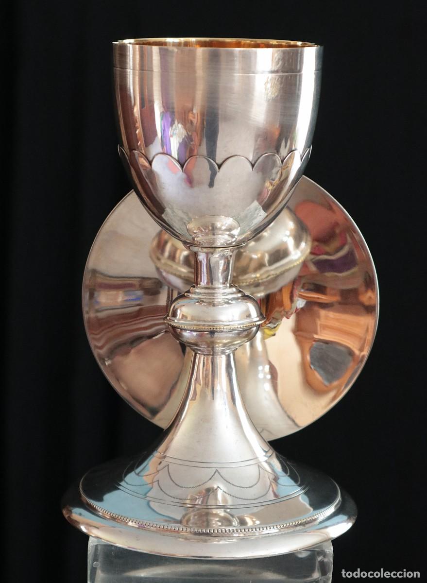 Antig&uuml;edades: C&aacute;liz lit&uacute;rgico y patena elaborados en lat&oacute;n plateado. Pps. S. XX. Mide 20 cm de altura.