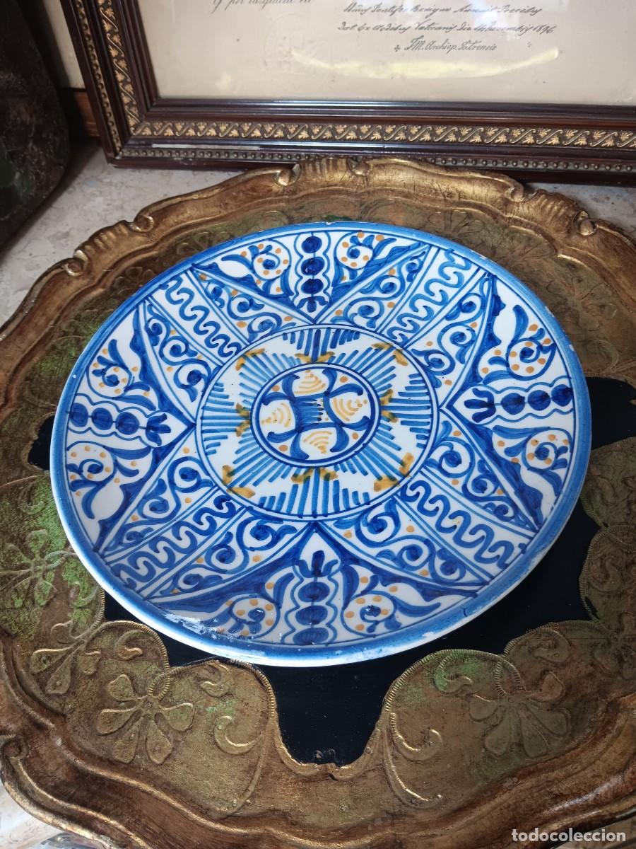 Antig&uuml;edades: cer&aacute;mica decorativa con un dise&ntilde;o geom&eacute;trico realizado en azul y amarillo sobre un fondo blanco. El