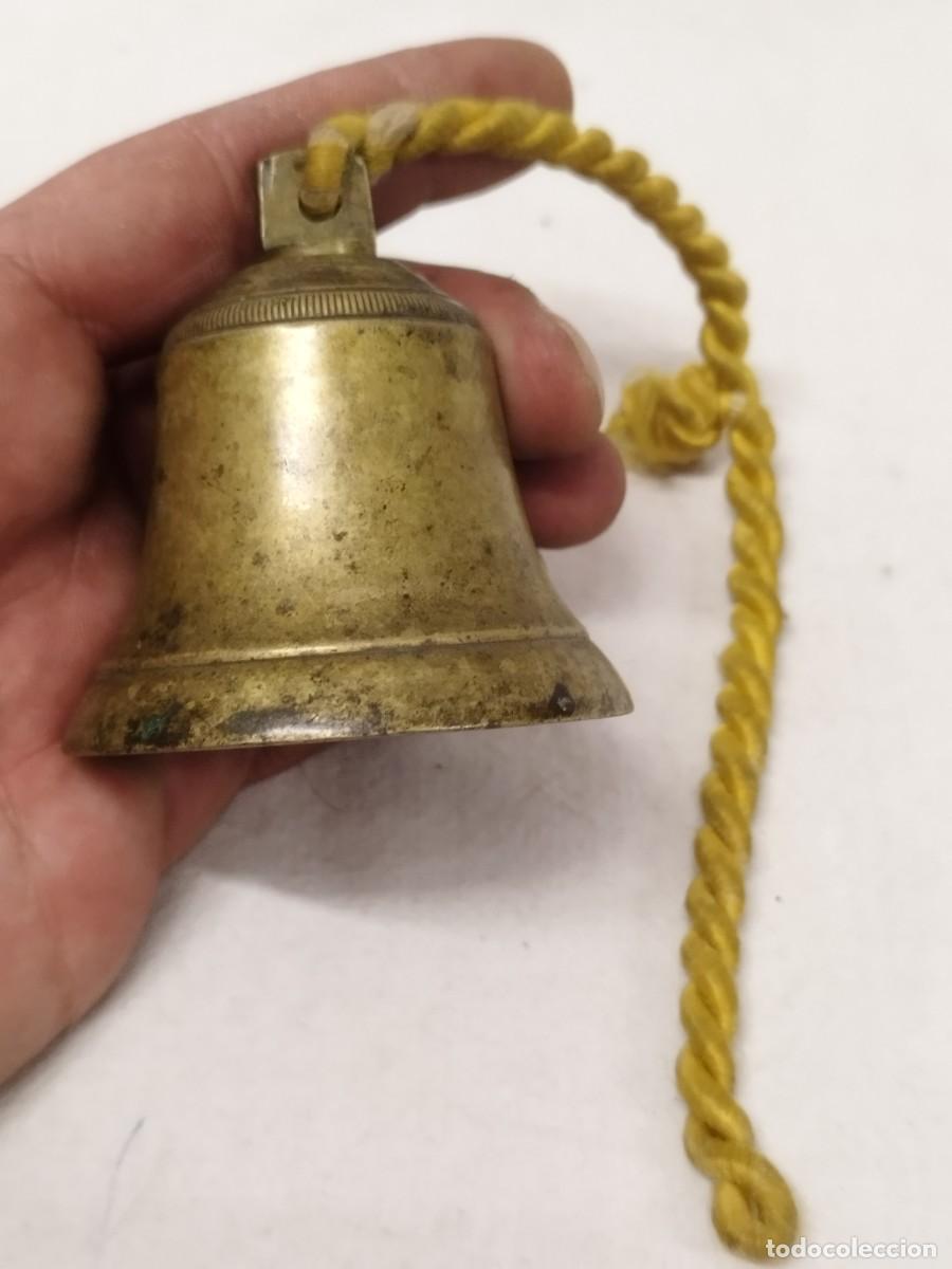Antig&uuml;edades: Antigua campana de bronce o lat&oacute;n, con cord&oacute;n de color amarillo. Sin badejo. Posiblemente sg. XIX.