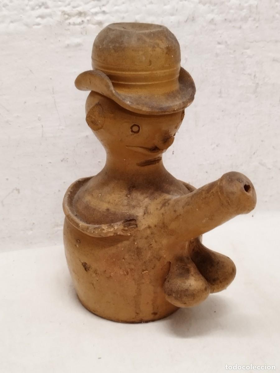 Antig&uuml;edades: Antiguo botijo con forma f&aacute;lica, hombre con sombrero.