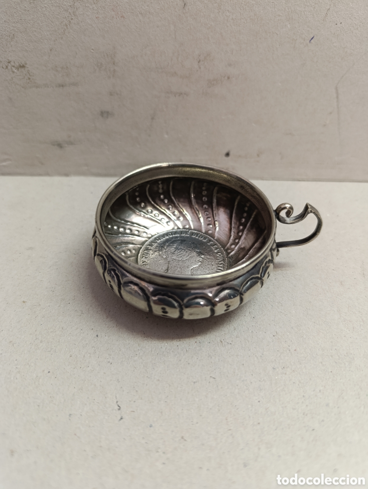 Antig&uuml;edades: TACITA DE METAL PLATEADO. CON ASA Y MONEDA EN LA PARTE DEL FONDO.