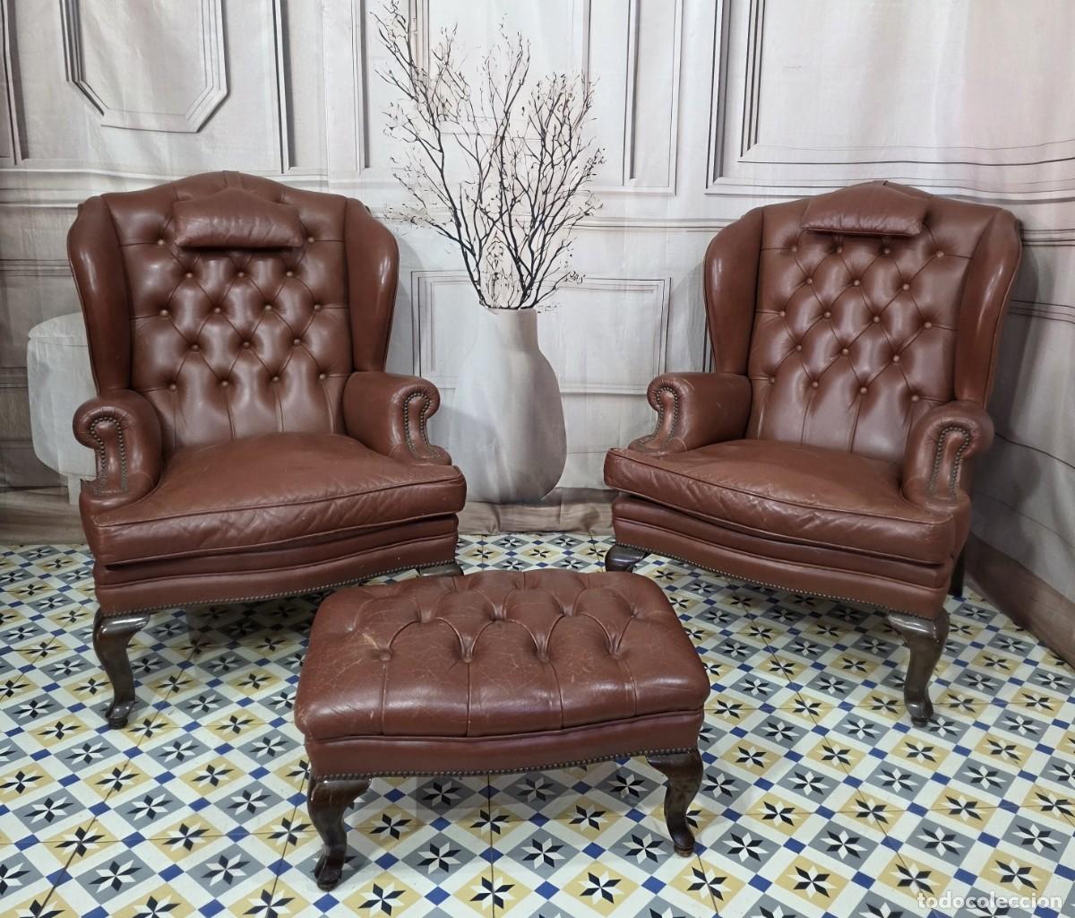 Antig&uuml;edades: Juego de sillones orejeros Chesterfield de cuero marr&oacute;n y reposapi&eacute;s