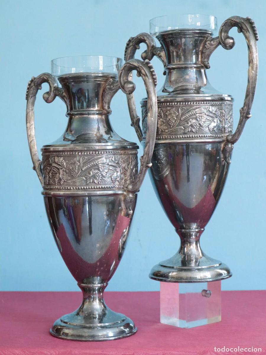 Antig&uuml;edades: Jarrones o &aacute;nforas de altar elaborados en metal plateado. Pps. S. XX. Miden 42 cm de altura.