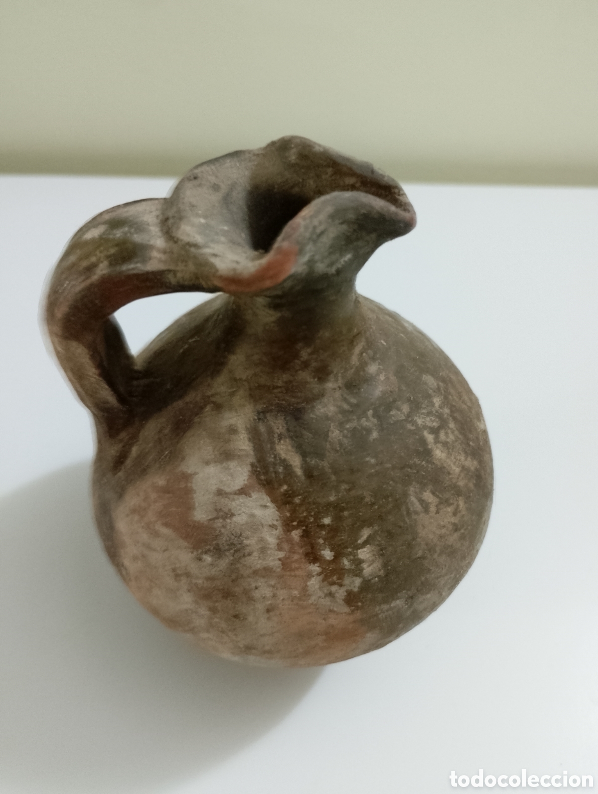 Antig&uuml;edades: Vasija antigua con asa con una altura aproximada de 12 cm y di&aacute;metro aproximado 9cm