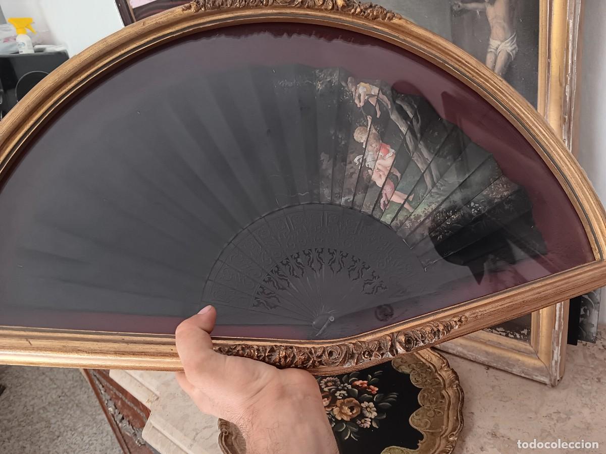 Antig&uuml;edades: abaniquera de madera con acabado dorado que contiene un abanico antiguo protegido por un cristal sem