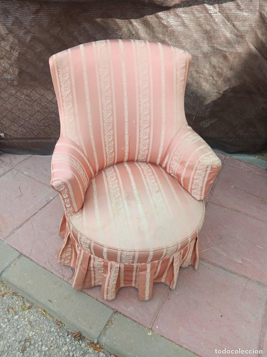 Antig&uuml;edades: sill&oacute;n descalzador de estilo vintage tapizado en tela rosa con rayas y motivos florales.