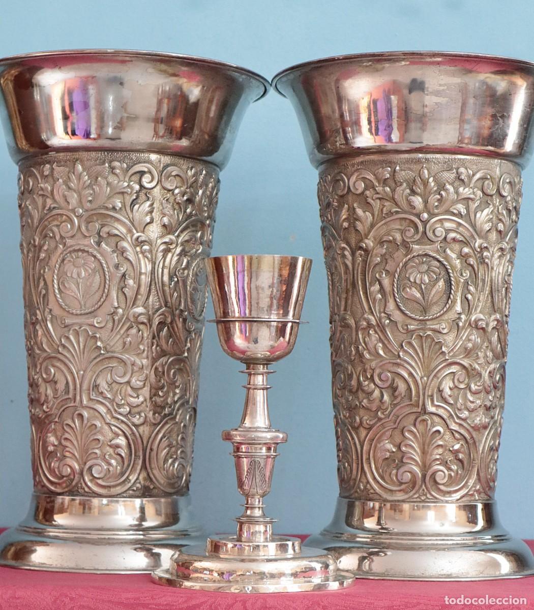 Antig&uuml;edades: Grandes jarrones o &aacute;nforas de altar elaborados en metal cincelado. Med. S. XX. Miden 40 cm de altura