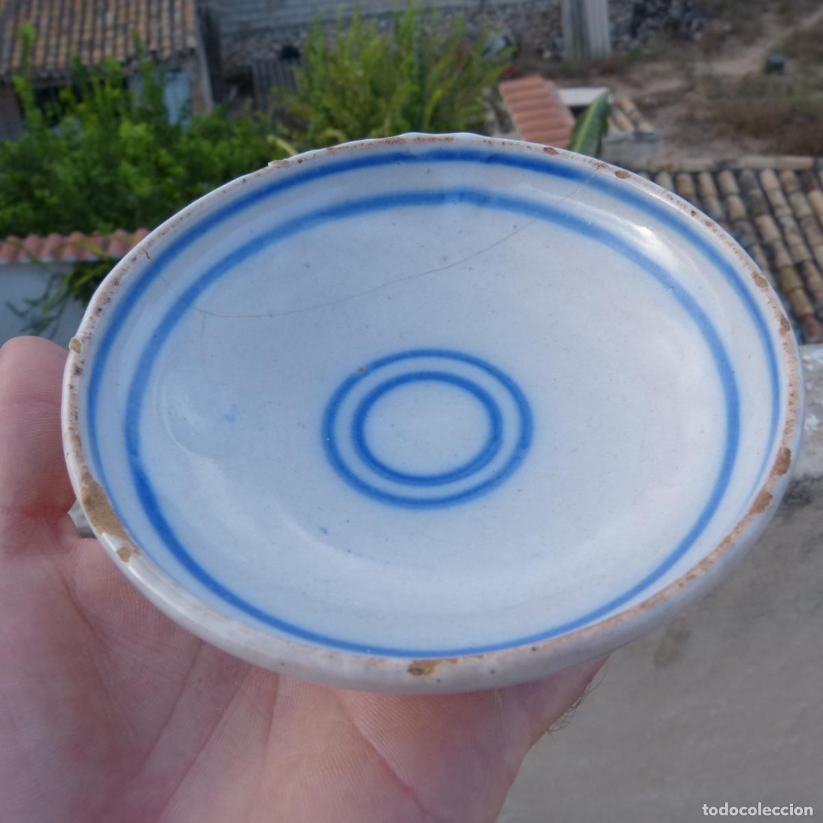 Antig&uuml;edades: Peque&ntilde;o plato en ceramica tradicional blanca con circulos en azul, 12cm, 137gr. Roto y pegado.