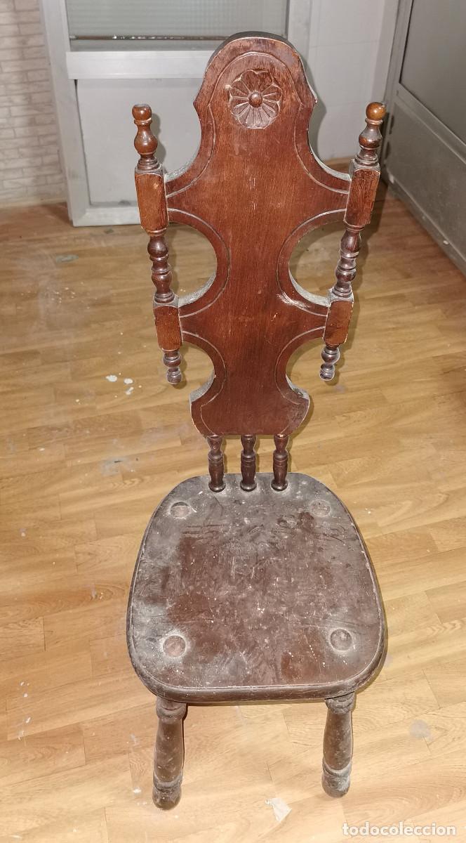 Antiquit&eacute;s: Silla baja antigua de madera tallada artesanal con elementos torneados y molduras decorativas.