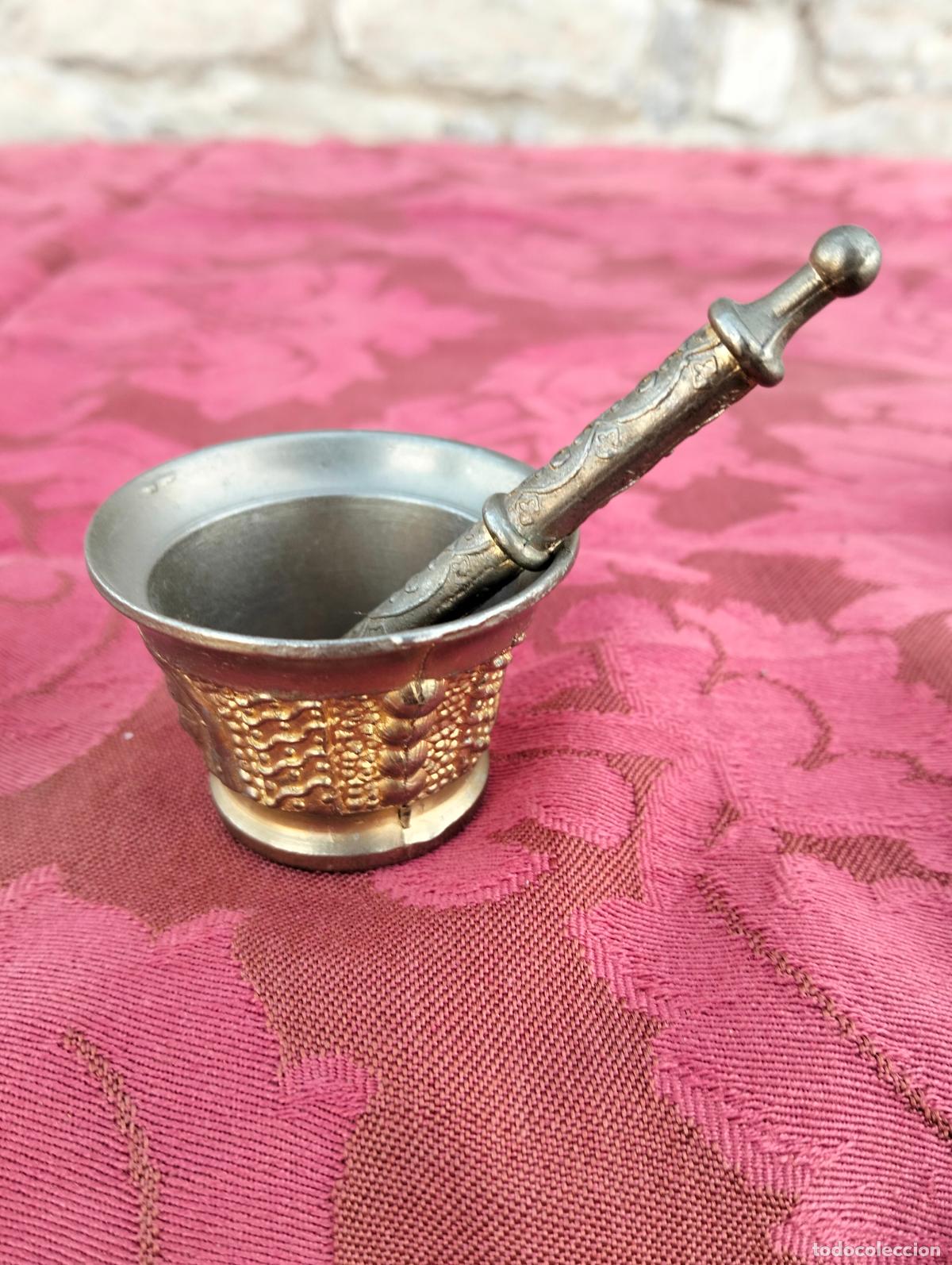 Antig&uuml;edades: Antiguo mortero de bronce lat&oacute;n con mano de mortero con caras de los a&ntilde;os 60