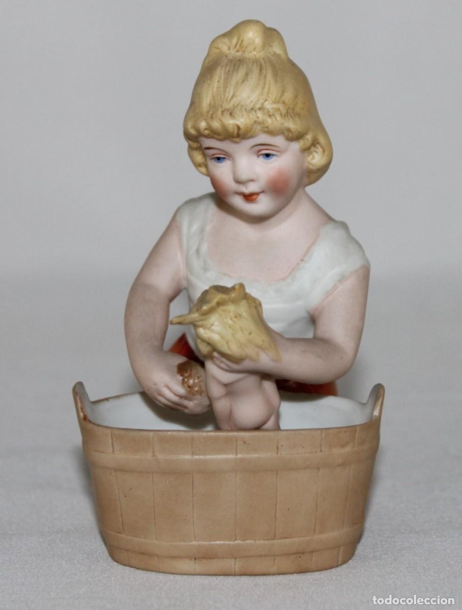 Antig&uuml;edades: Ni&ntilde;a ba&ntilde;ando a su mu&ntilde;eca en biscuit policromado. Principios siglo XX