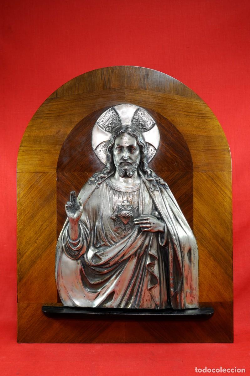 Antig&uuml;edades: Gran Sagrado Coraz&oacute;n de Jesus en metal ba&ntilde;ado en Alpaca sobre tablero chapeado de Roble, a&ntilde;os 40.