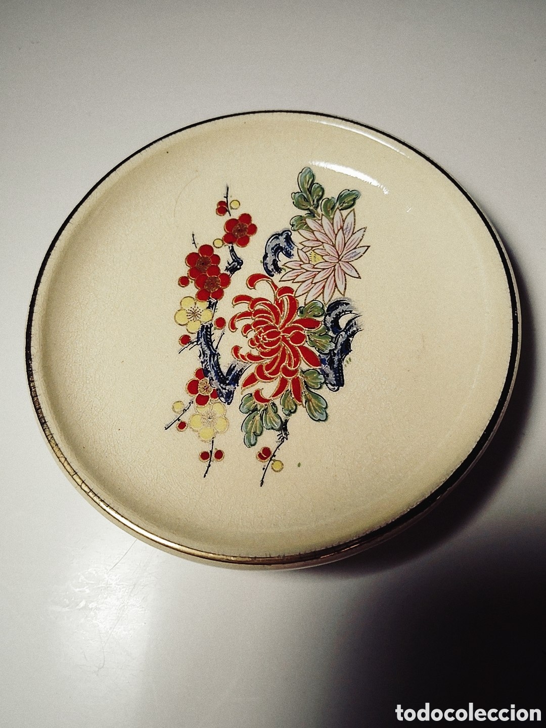 Antig&uuml;edades: Plato cer&aacute;mico japon&eacute;s. 9 cm de di&aacute;metro. Motivos florales. Colores esmaltados. Filo dorado
