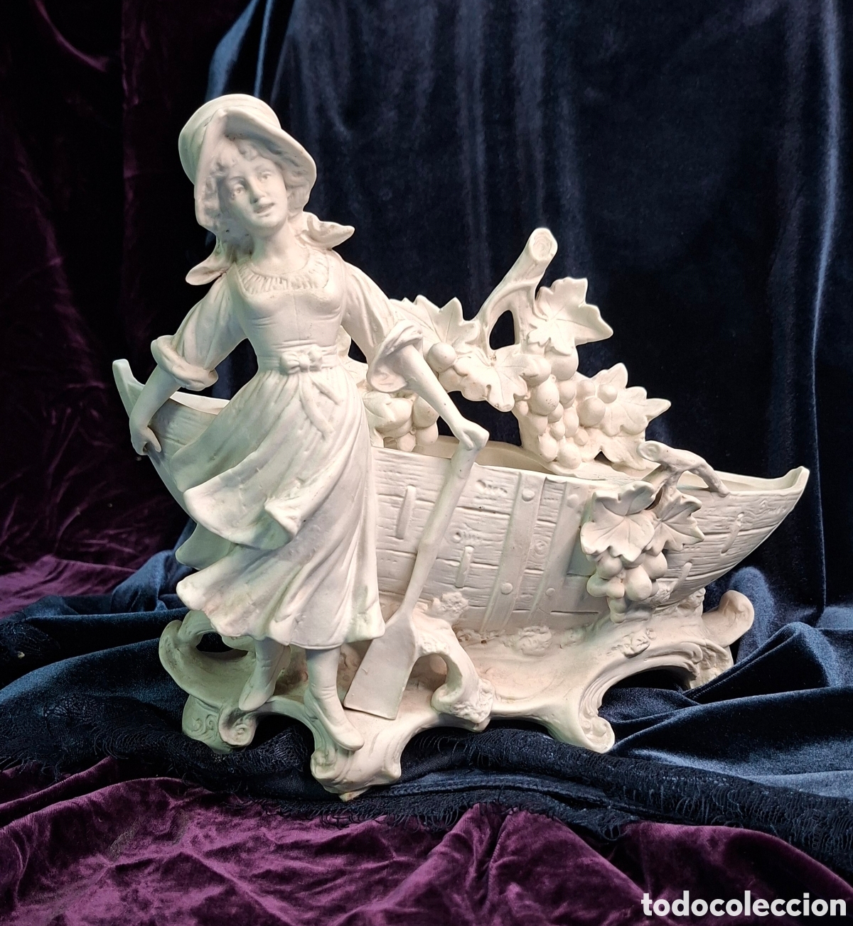 Antig&uuml;edades: Figura en biscuit de se&ntilde;ora vendimiando en barca &ndash; 22 cm x 27 cm