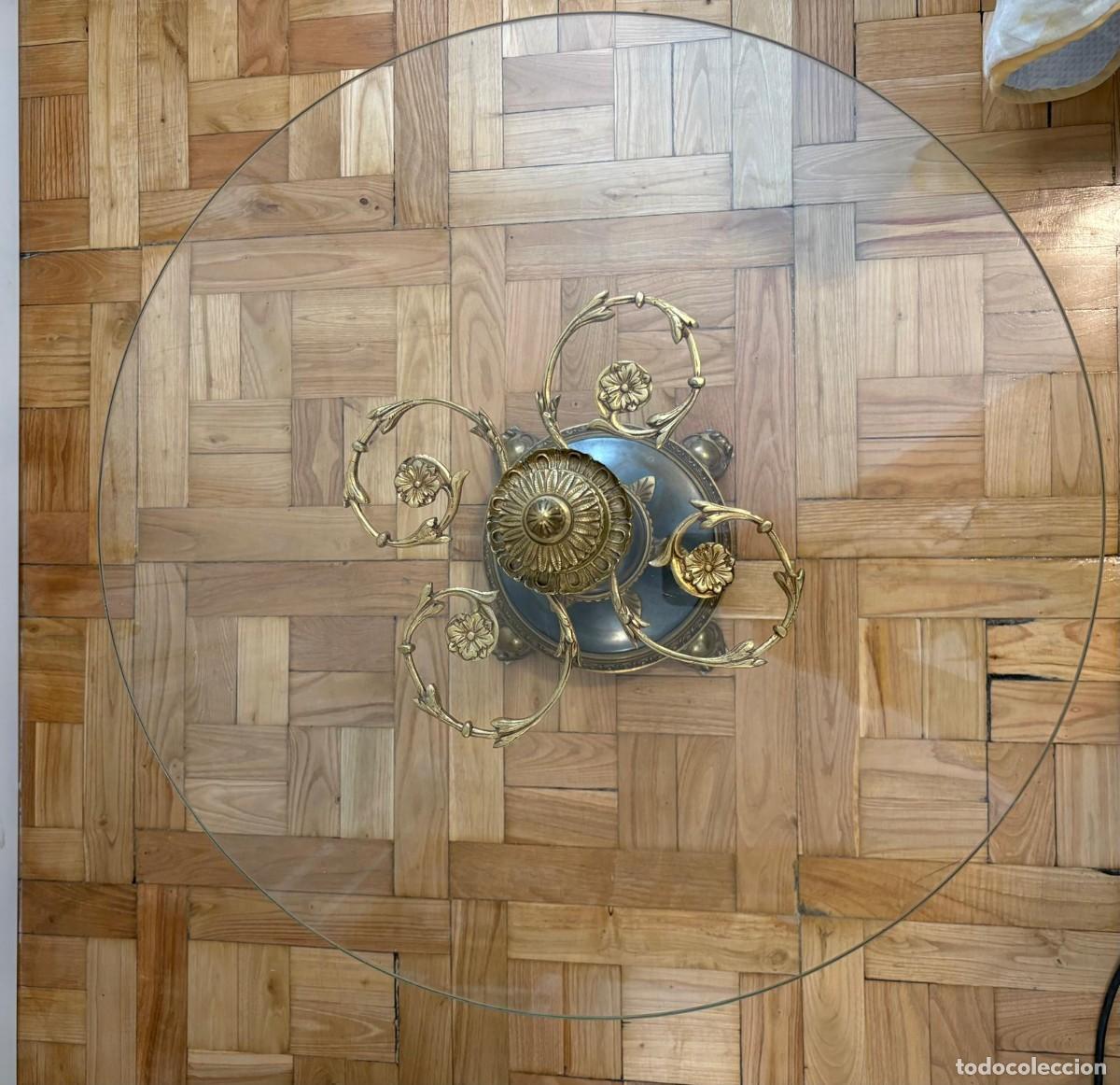 Antiques: mesa con superficie de cristal y base de metal con detalles dorados.