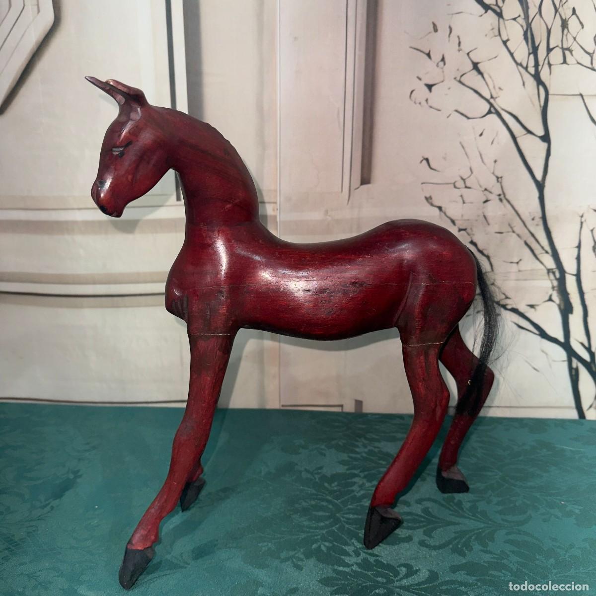 Arte: Escultura artesanal de madera tallada que representa un caballo de color caoba rojiza.