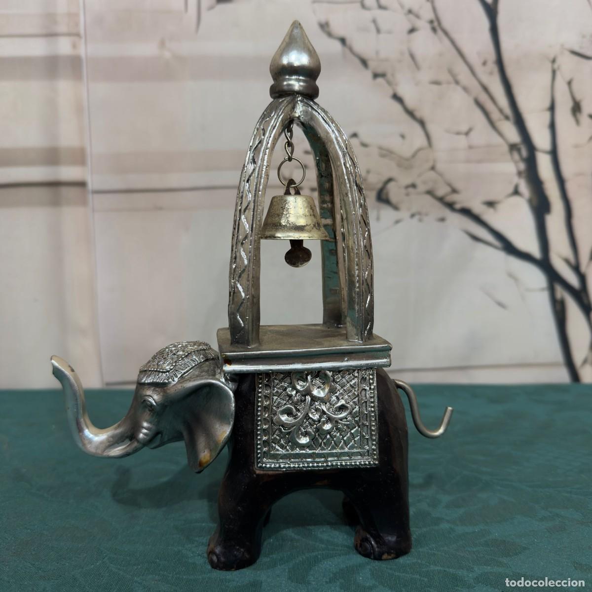 Arte: Figura decorativa elefante de madera con detalles plateados y una campana colgante