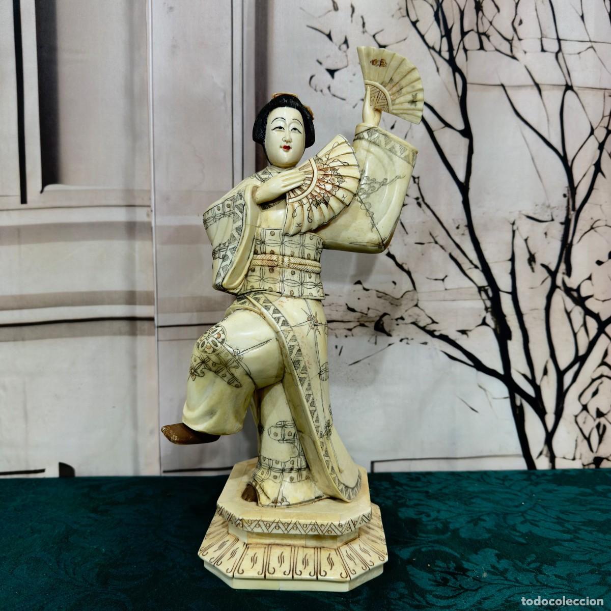 Arte: Figura representa a una geisha japonesa bailando con abanicos, tallada en hueso