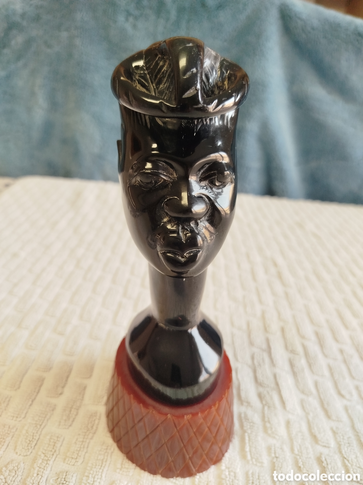Arte: Escultura busto hombre africano sobre peana rojiza.