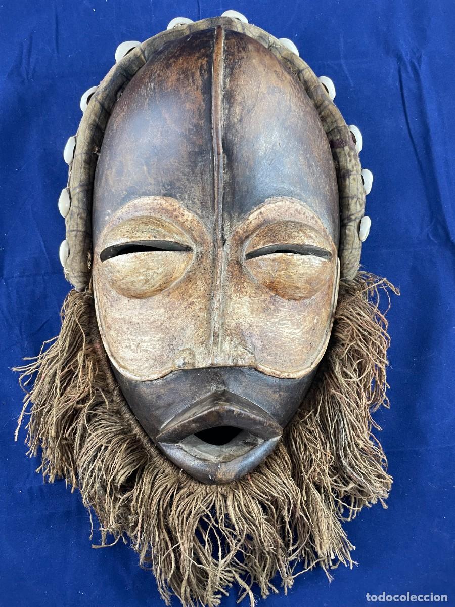Arte: M&aacute;scara africana antigua de madera con caur&iacute;es y rafia. Arte tribal, mediados siglo XX