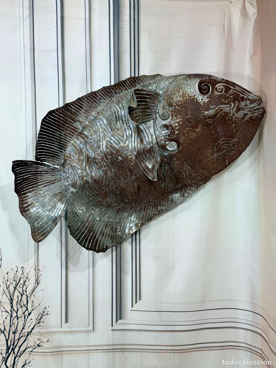 Arte: Escultura de pared de metal que representa un pez con acabado oxidado.