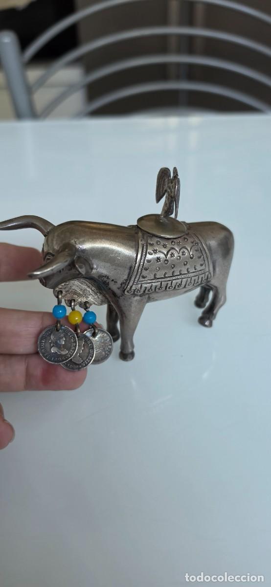 Arte: Muy curioso recipiente en plata o similar toro con tres monedas de medio real de plata