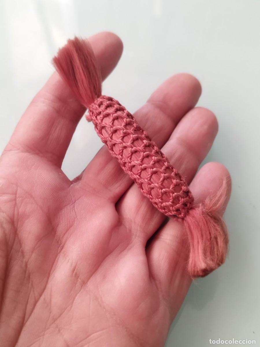 Artesan&iacute;a: Accesorio artesanal de forma tubular de macram&eacute; o red de cord&oacute;n trenzado.