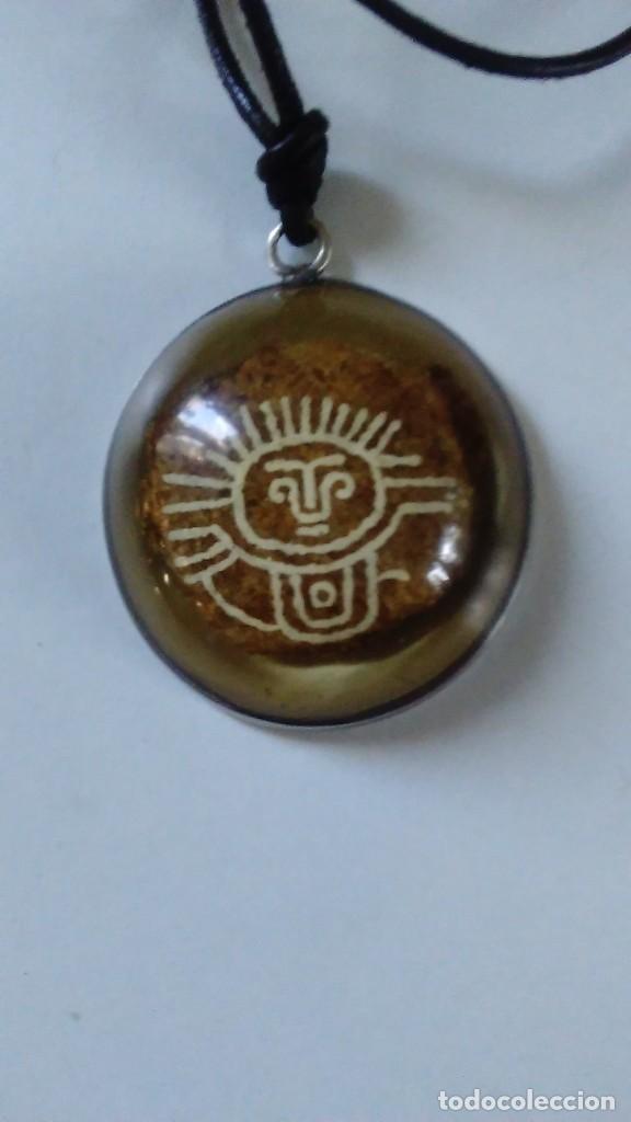 Joalharia: Colgante con piedra pintada con motivo azteca engarzado en material transparente con un aro de plata