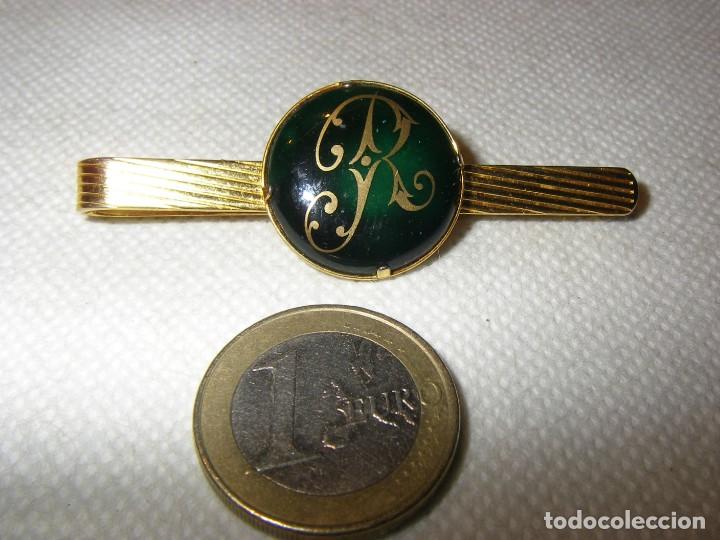 Joaillerie: Pisacorbatas de metal dorado y vidrio o piedra central con la letra R.