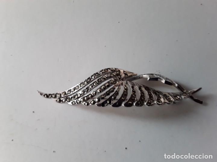 Joalharia: Broche de metal plateado. Las protuberancias o adornos son de metal tallado y facetado