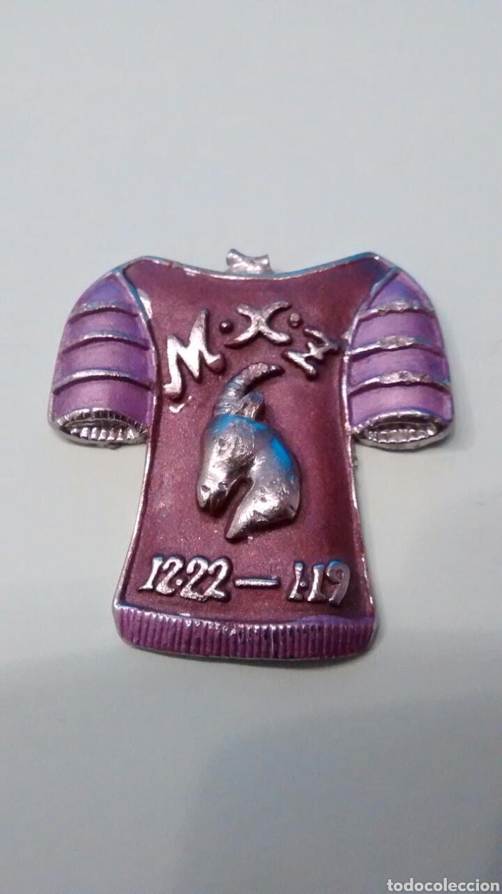 Joalharia: COLGANTE DE UNA CAMISETA O ARMADURA EN METAL CON LA INSCRIPCION M.X.Z 12.22-1.19