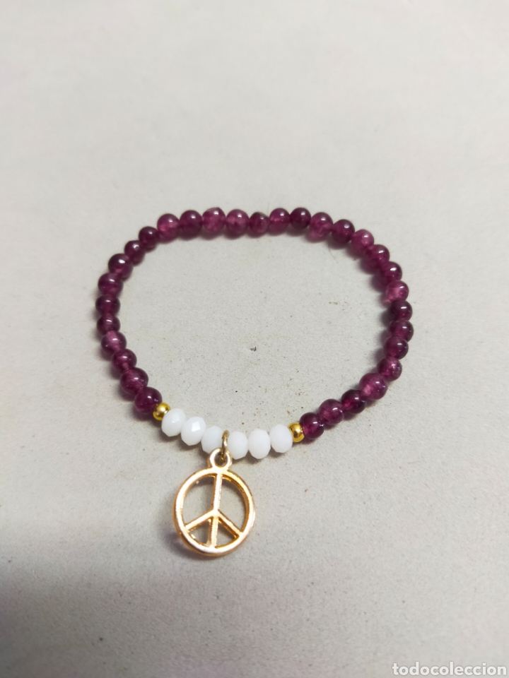 Gioielleria: PULSERA DE CUENTAS GRANATE Y BLANCAS CON SIMBOLO SE LA PAZ EN METAL DORADO.