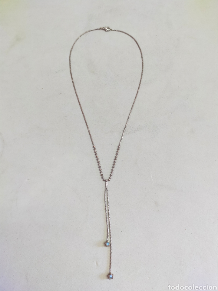 Joalharia: CADENA GARGANTILLA EN METAL PLATEADO CON DETALLES DE FLORES AZULES EN EXTREMO.