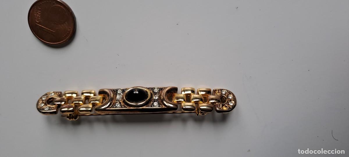 Gioielleria: Broche alargado de metal dorado con piedra oscura en el centro y zirconitas. Con cierre de segiridad