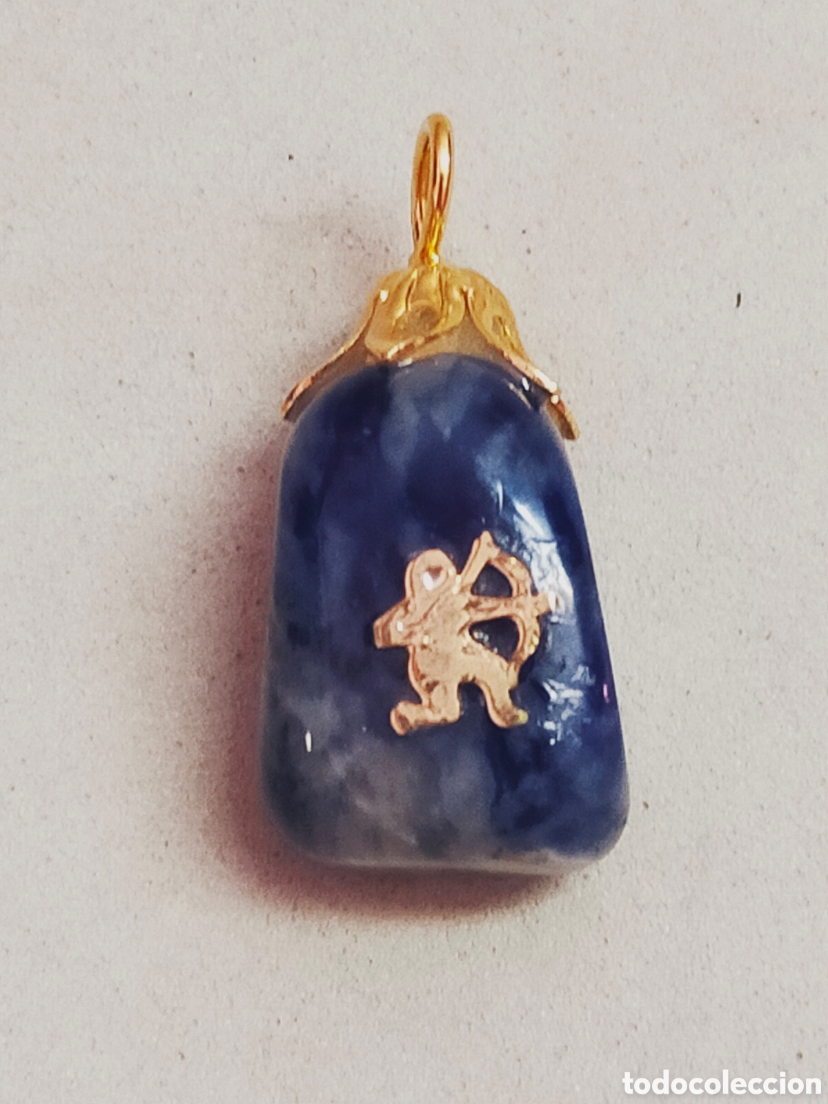 Joyeria: COLGANTE DE SAGITARIO EN PIEDRA SODALITA Y DETALLES EN METAL DORADO.