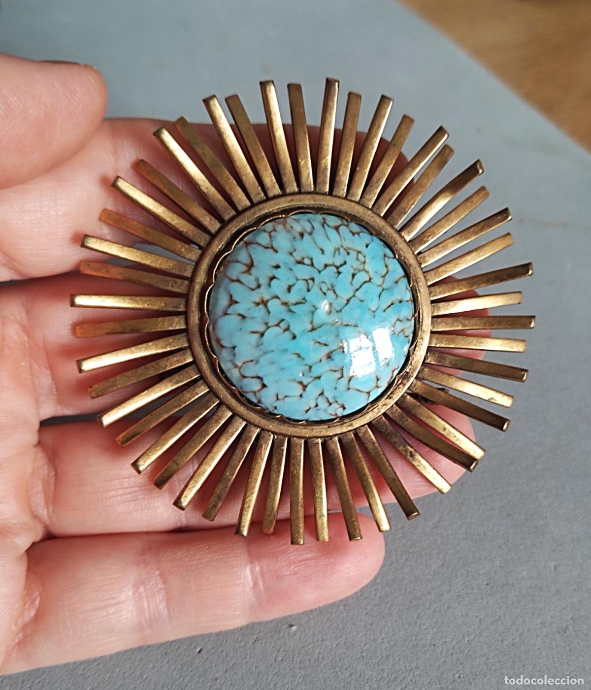 Joyeria: Bonito broche dorado, forma de sol, o flor, con piedra azul.
