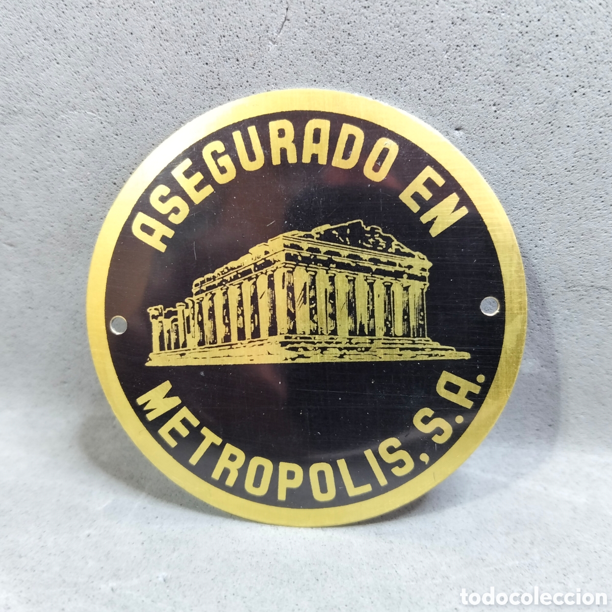 Carteles: Antigua chapa de asegurado. Metropolis S.A. Compa&ntilde;&iacute;a Nacional de Seguros. A&ntilde;os 60. Fondo color oro