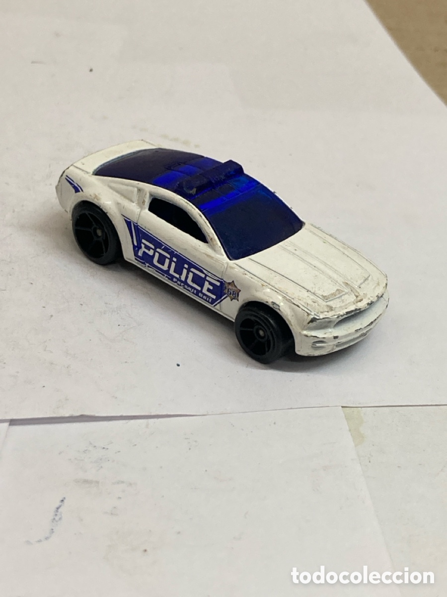Coches a escala Hot Wheels: coche de juguete Hot Wheels modelo Ford Mustang GT Concept de color blanco con gr&aacute;ficos de polic&iacute;a