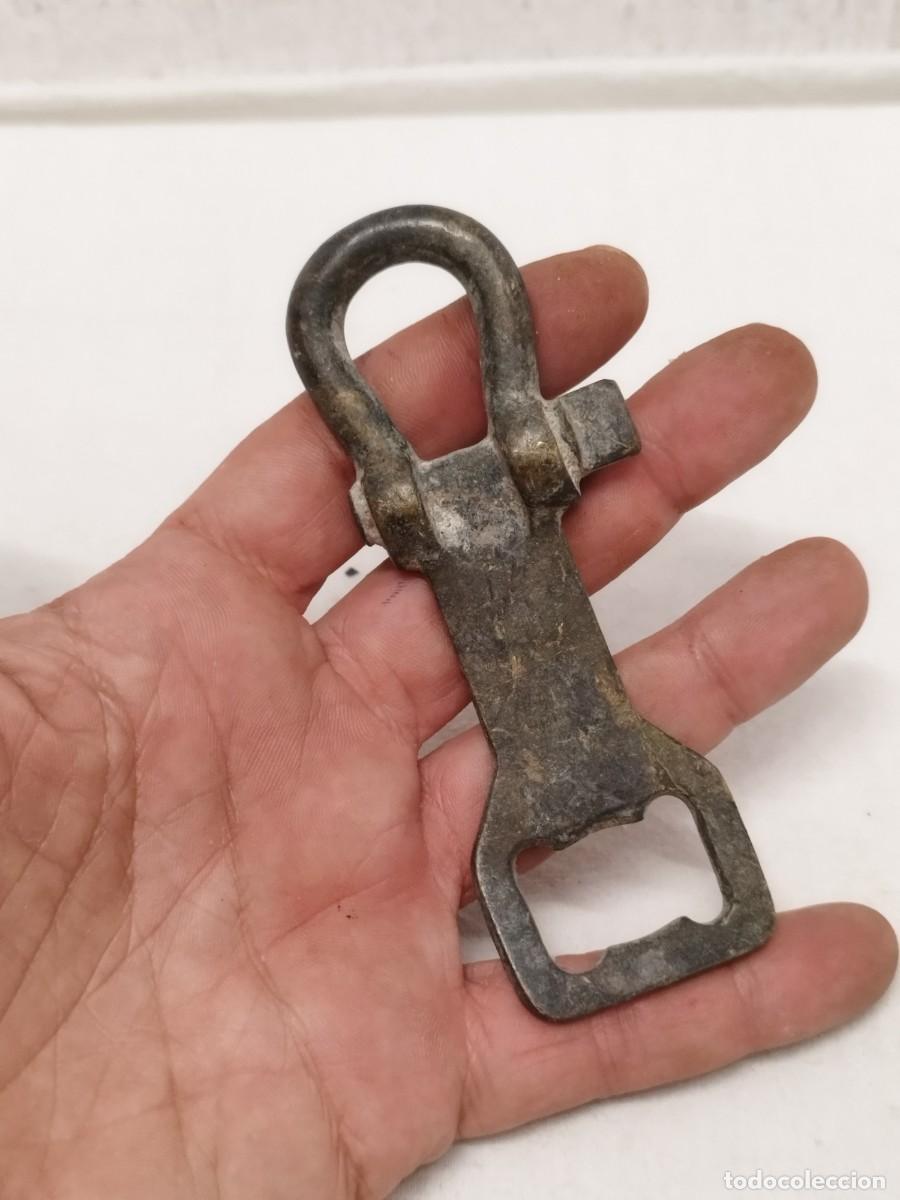 Abrebotellas y sacacorchos de colecci&oacute;n: Antiguo abridor de botellas chapas, en forma de mosquet&oacute;n de seguridad. En bronce o lat&oacute;n.