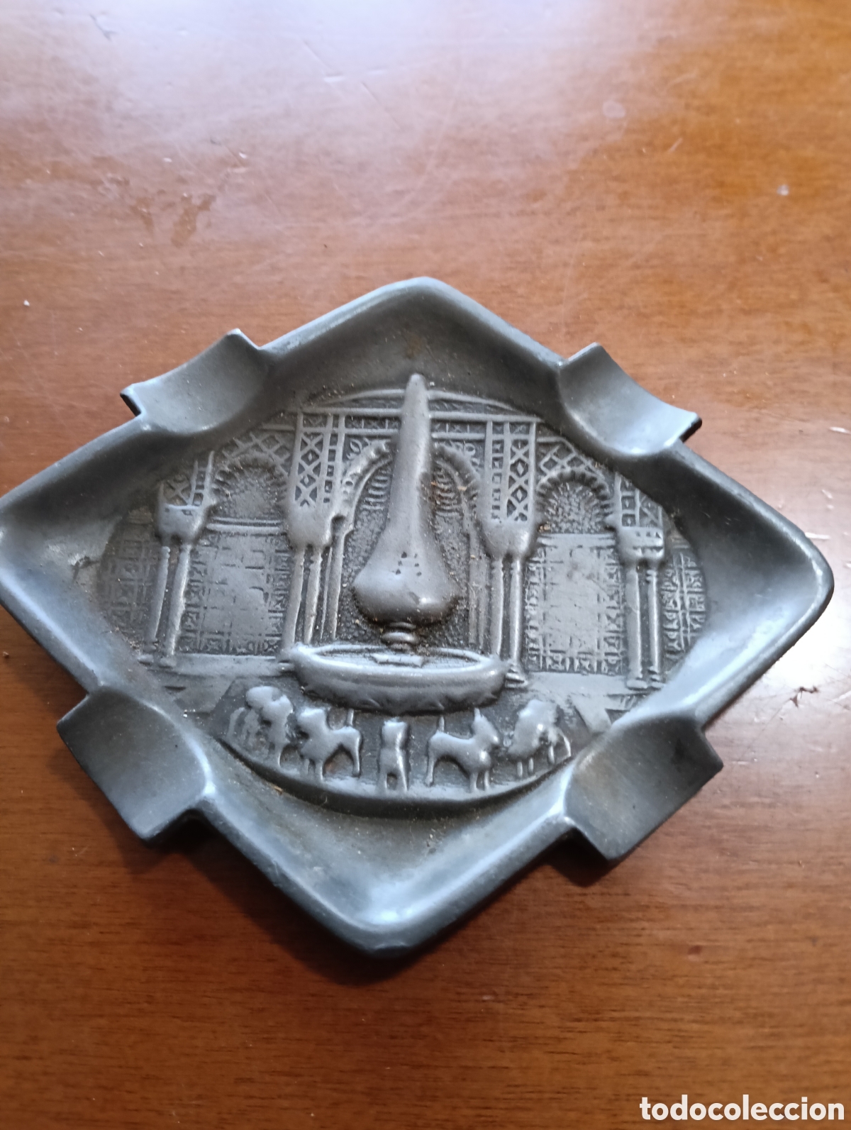 Ceniceros: &nbsp;El cenicero presenta un relieve con elementos arquitect&oacute;nicos que evocan arcos, columnas y una fuen