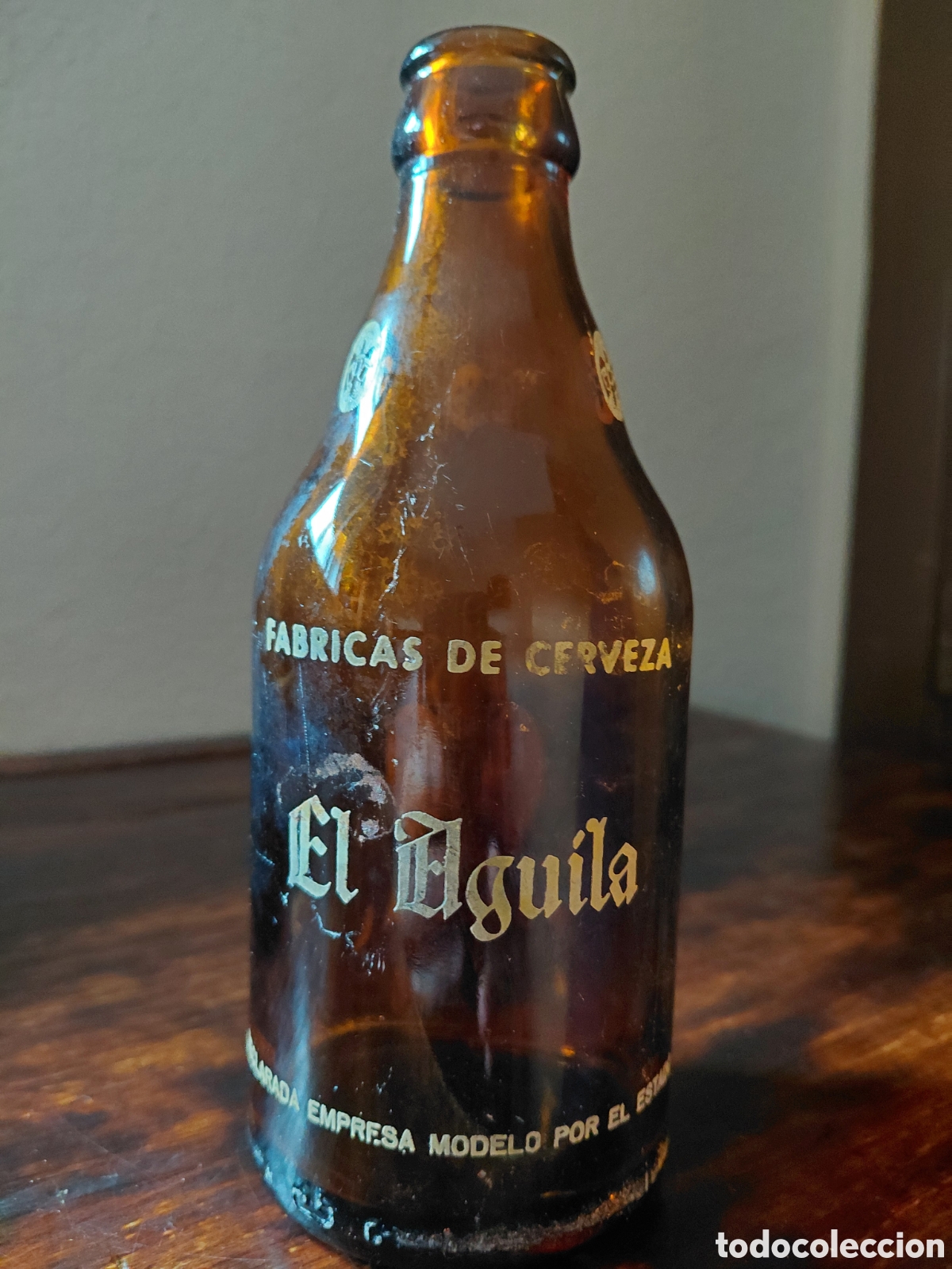Coleccionismo de cervezas: Antigua botella de cerveza el aguila, 33 cl. Declarada empresa modelo por el estado. Rareza.