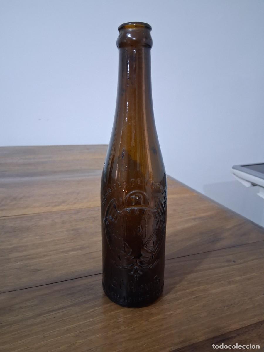 Coleccionismo de cervezas: Botella en relieve de cerveza El aguila tercio cristal marron ambar